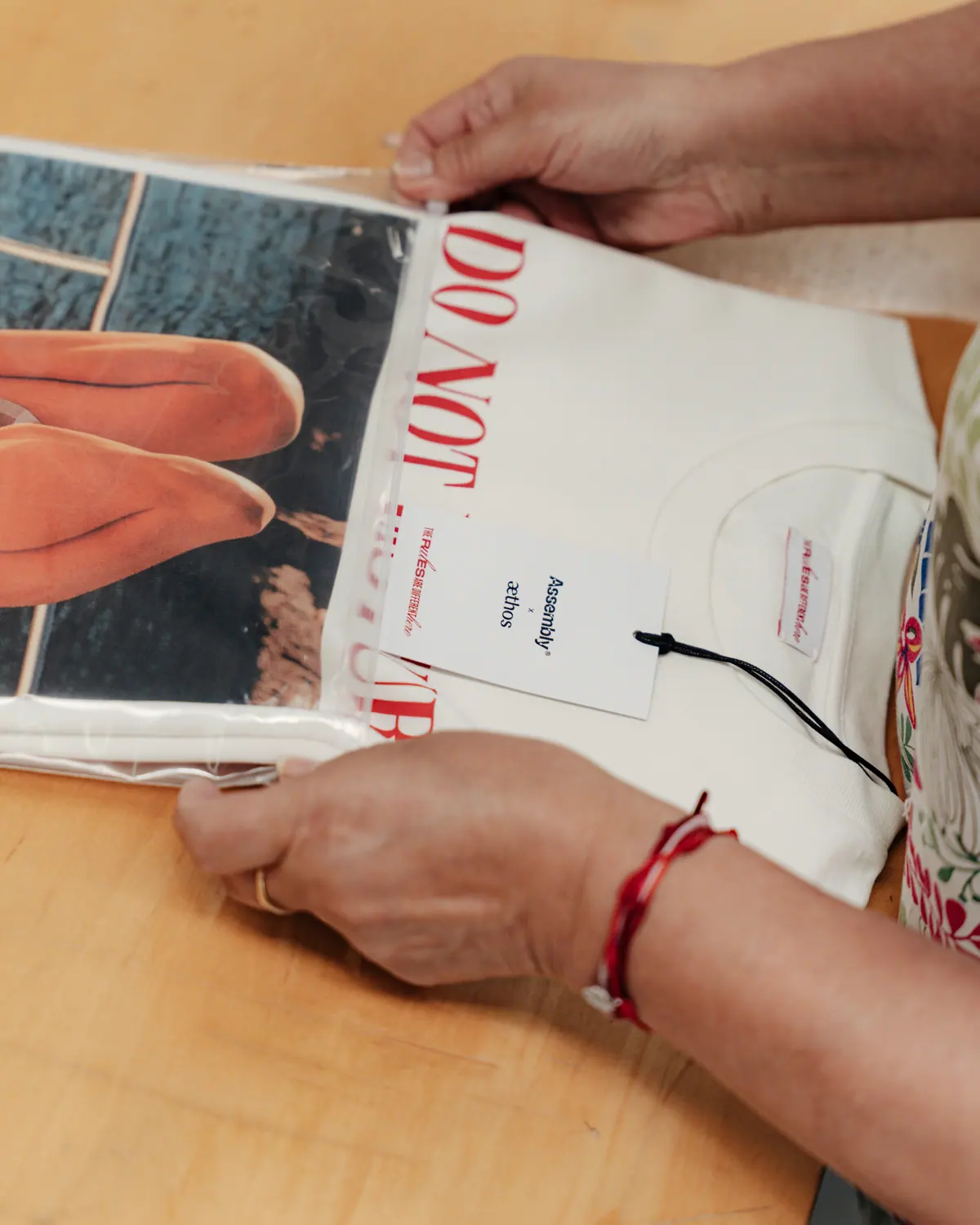 Hands attaching a hangtag to a printed white T-shirt