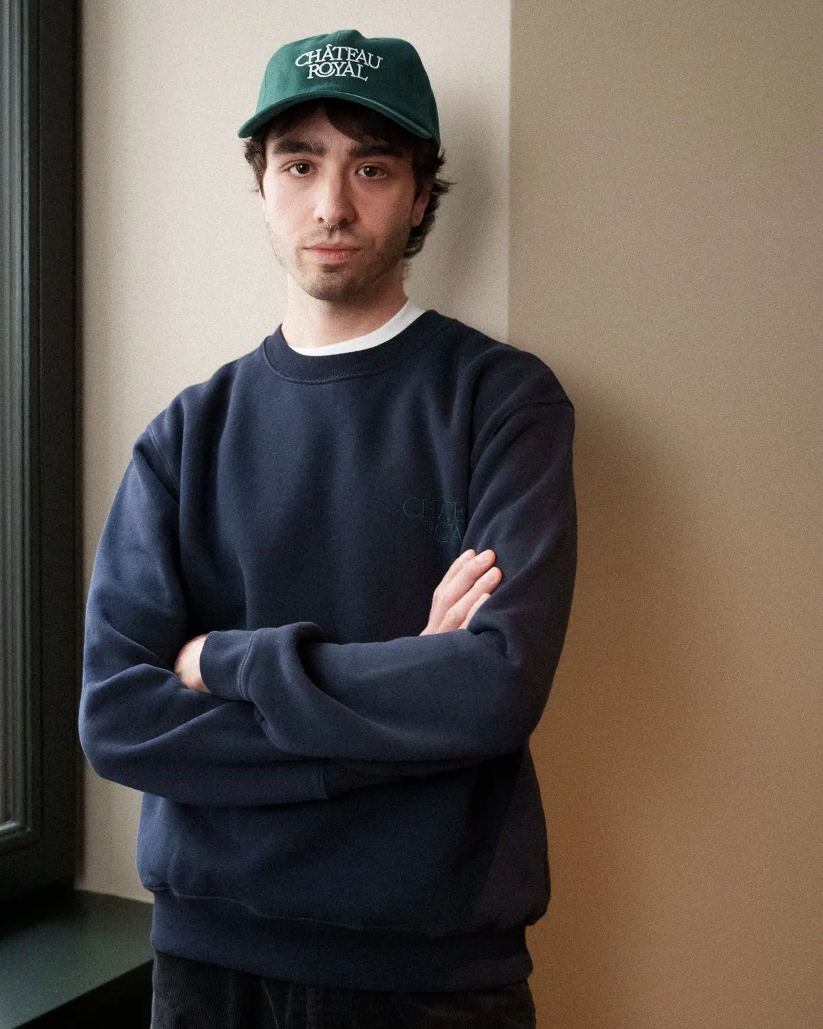 Château Royal navy crewneck sweatshirt worn in a hotel room, arms crossed