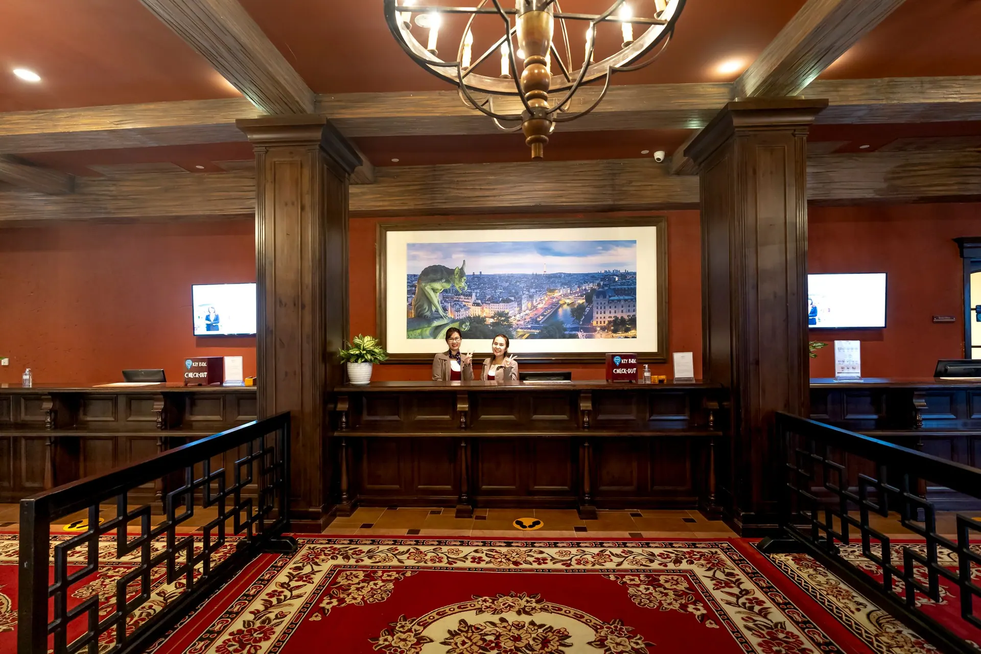 Two front-office staff behind a long wooden desk in a hotel lobby