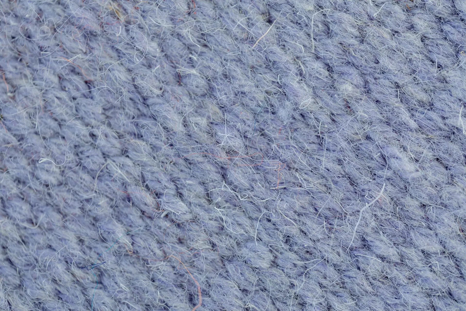 Macro of a blue-grey wool knit surface showing the yarn structure