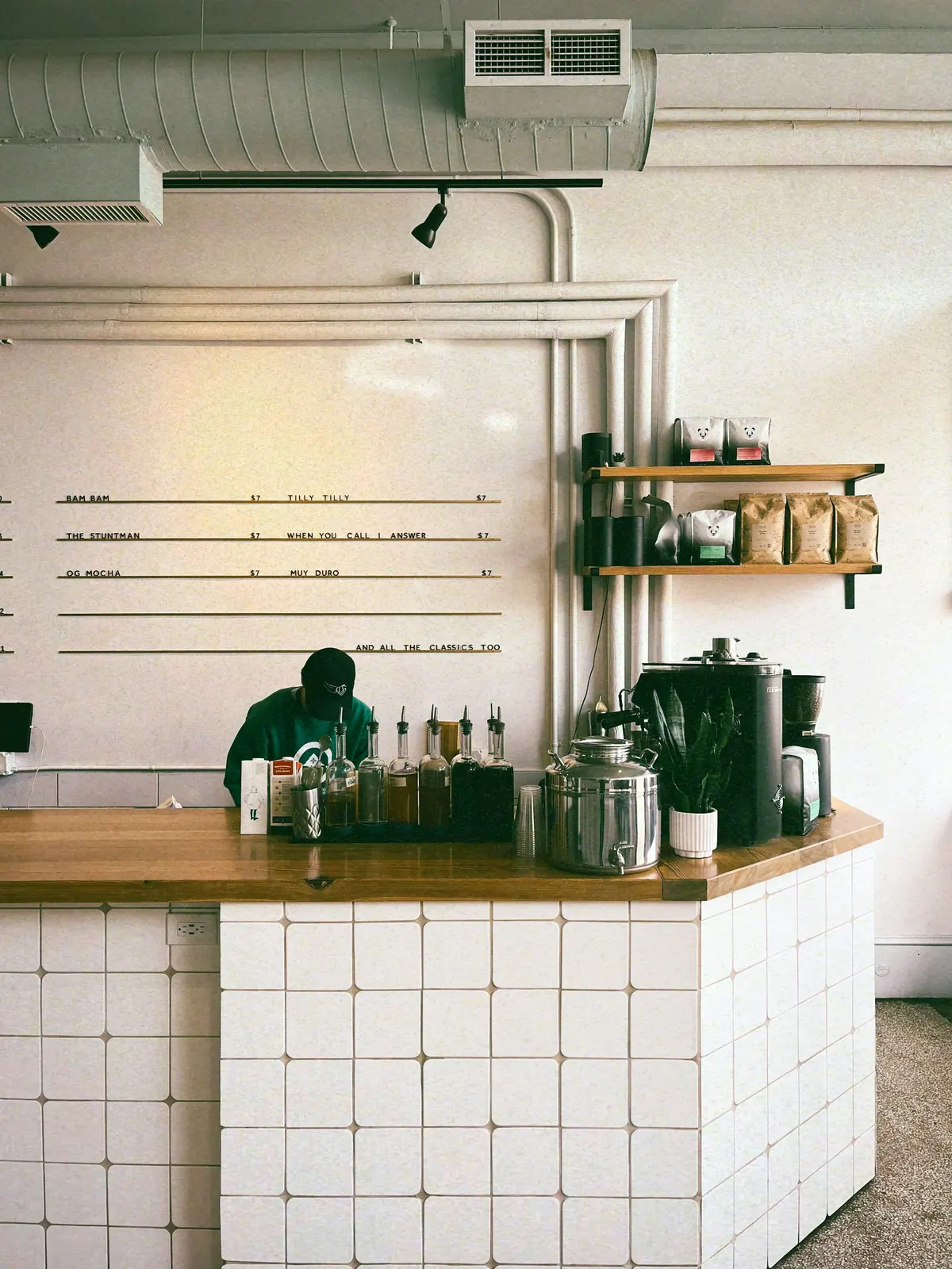 Barista behind the tiled counter of a small café