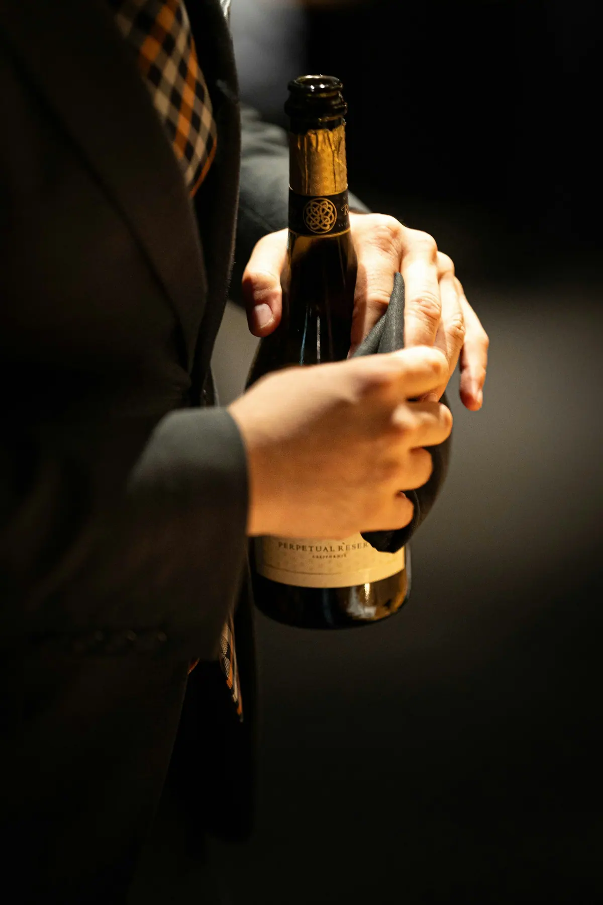 Sommelier in a dark suit presenting a bottle with a cloth